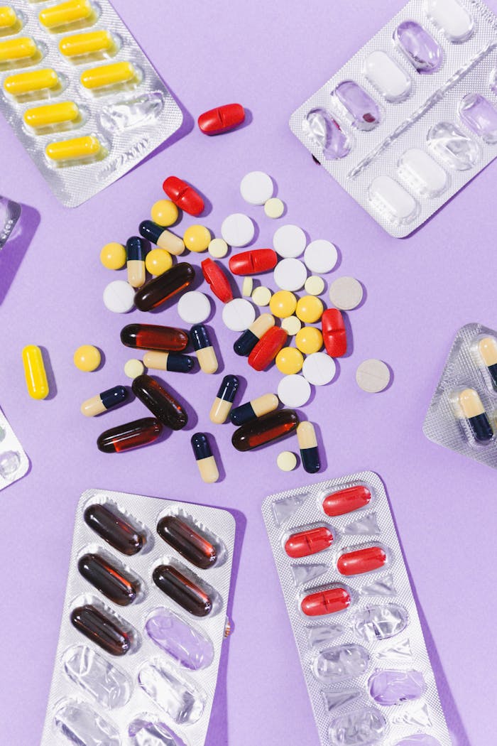 Close-up of various pills and capsules on a purple backdrop, showcasing pharmaceutical diversity.